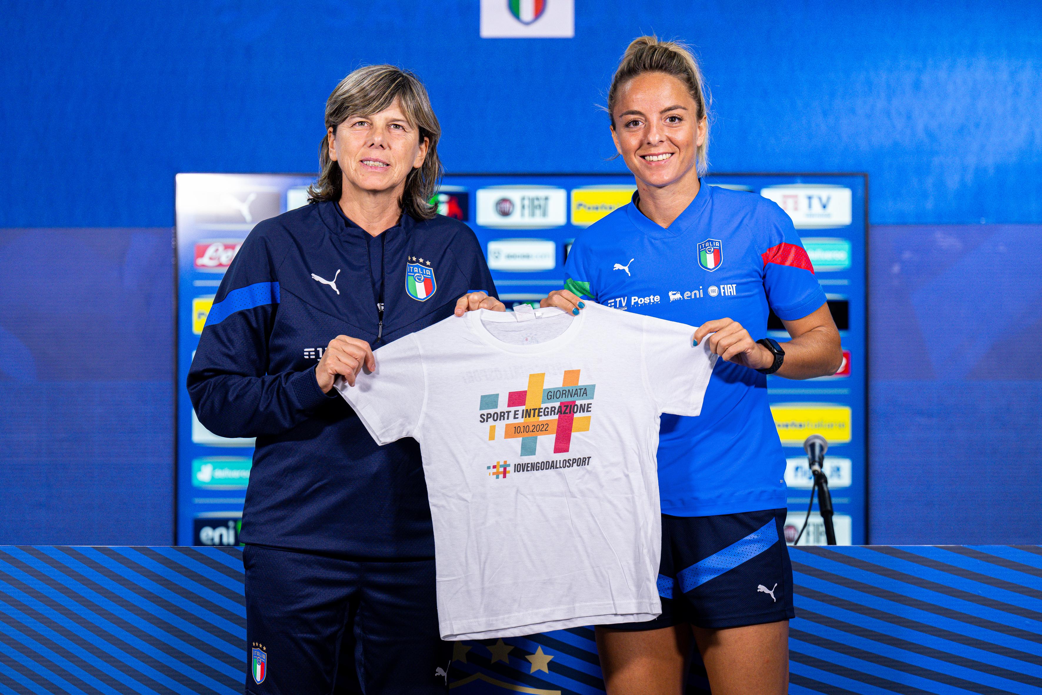 GENOA, ITALY - OCTOBER 09: Milena Bertolini head coach of Italy (L) and Martina Rosucci of Italy show a t-shirt dedicated to the “Sports and integration day” after a press conference at Stadio Luigi Ferraris on October 9, 2022 in Genoa, Italy. (Photo by Simone Arveda/Getty Images)