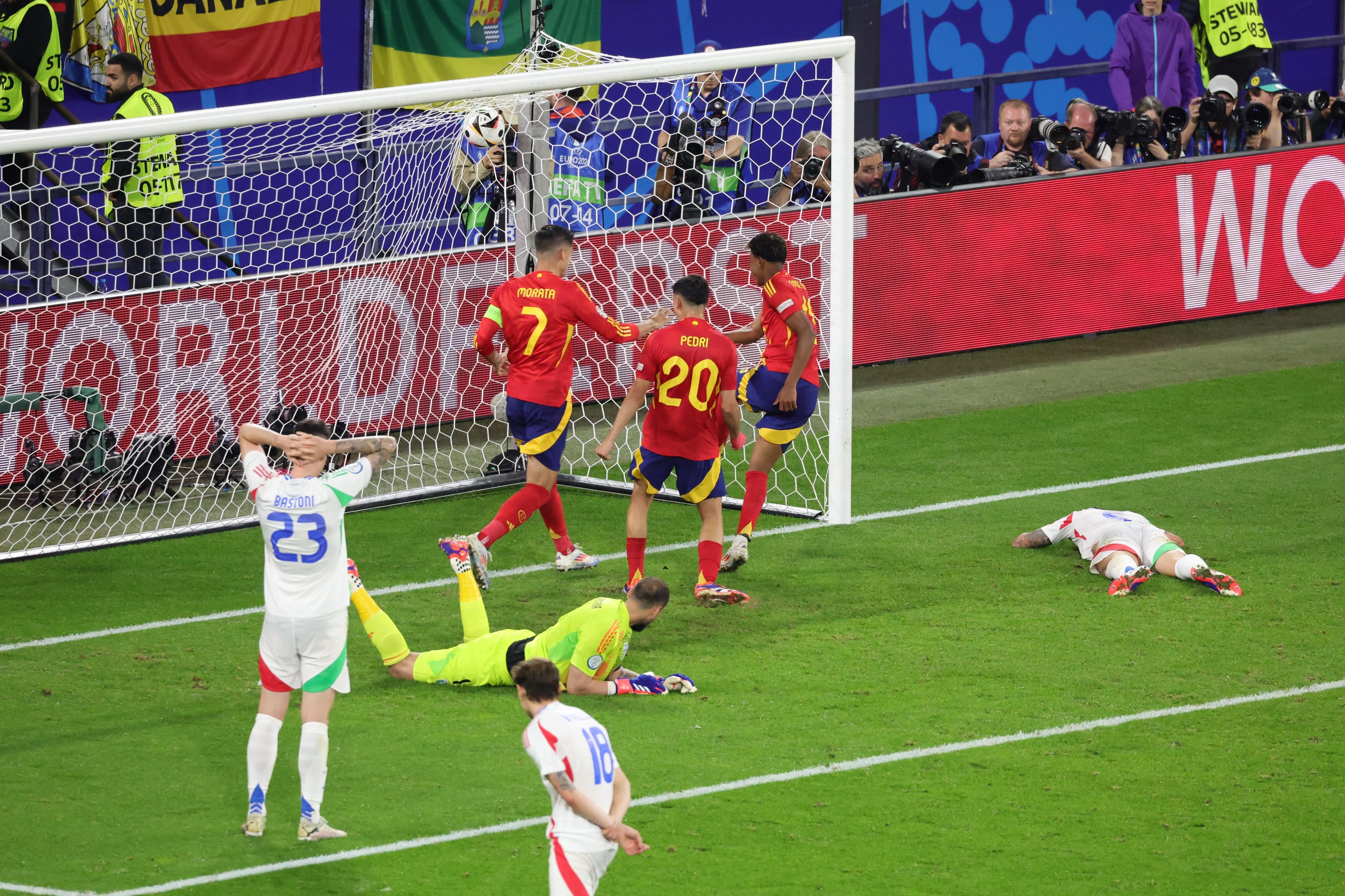 GELSENKIRCHEN, GERMANY - JUNE 20: Riccardo Calafiori of Italy lies dejected on the gras after scoring an own goal and the first goal for Spain as Lamine Yamal, Alvaro Morata and Pedri of Spain celebrate during the UEFA EURO 2024 group stage match between Spain and Italy at Arena AufSchalke on June 20, 2024 in Gelsenkirchen, Germany. (Photo by Andreas Rentz - UEFA/UEFA via Getty Images)