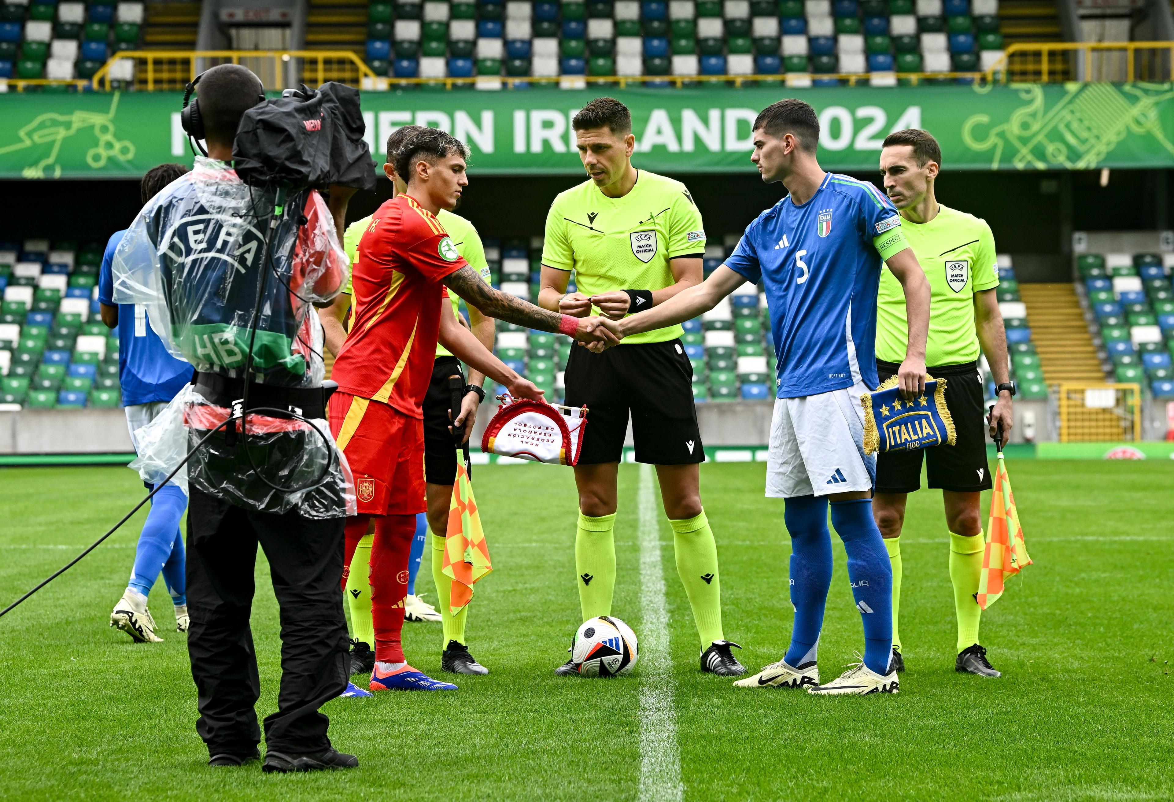 BELFAST, NORTHERN IRELAND - JULY 25: Referee Marian Barbu with team captains Gerard Hernandez of Spain and Luca Lipani of Italy before the UEFA European Under-19 Championship 2024 semi-final match between Italy and Spain at National Football Stadium at Windsor Park on July 25, 2024 in Belfast, Northern Ireland. (Photo by Seb Daly - Sportsfile/UEFA via Getty Images)